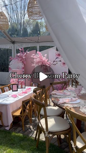 a table set up for a party with pink flowers on the tables and white chairs