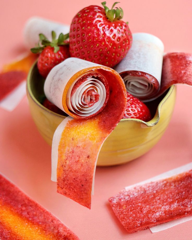 a bowl filled with candy and strawberries on top of a table