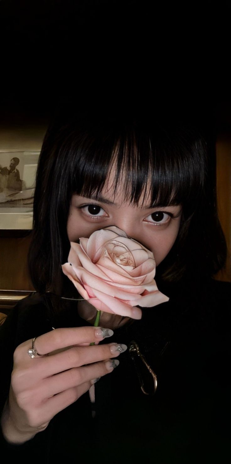 a woman holding a rose up to her face