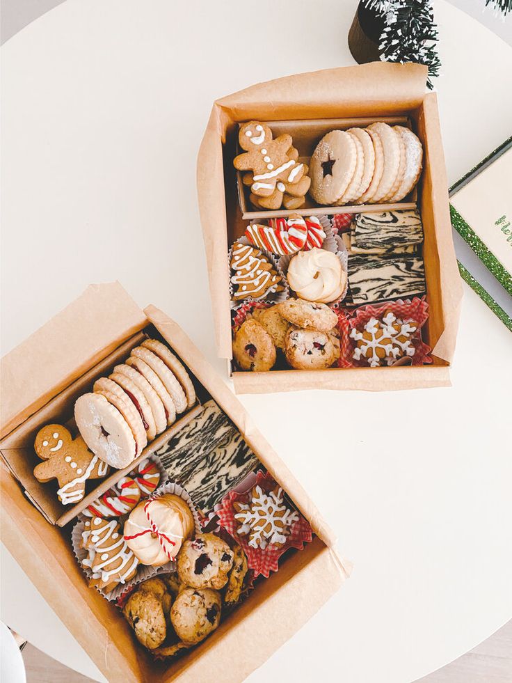 two boxes filled with assorted cookies on top of a table