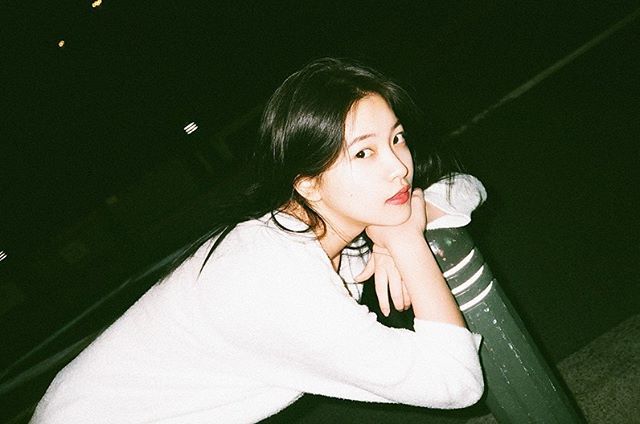 a woman sitting on top of a metal pole next to a parking meter at night