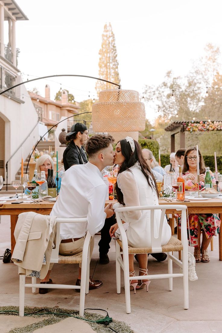 a group of people sitting around a table with food and drinks in front of them