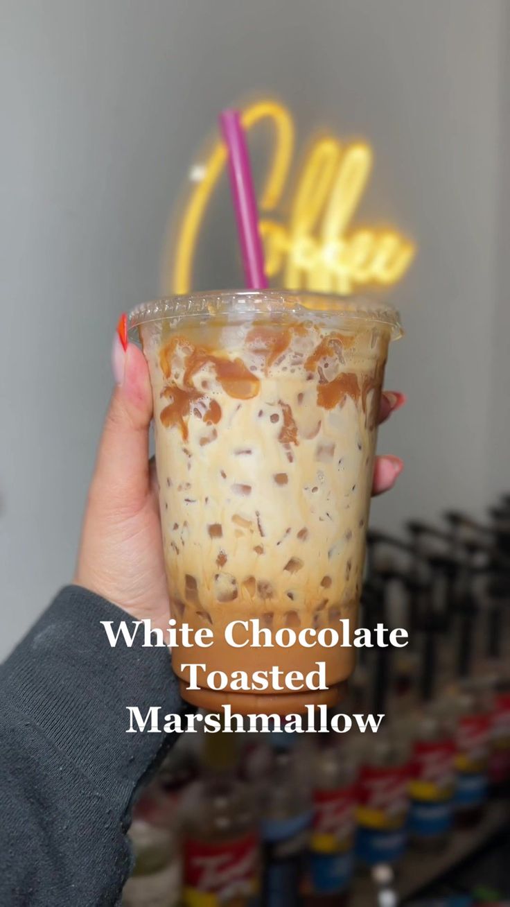 a person holding up a drink with the words white chocolate toasted marshmallow