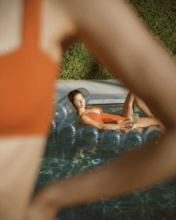 a woman in an orange swimsuit floating on top of a pool