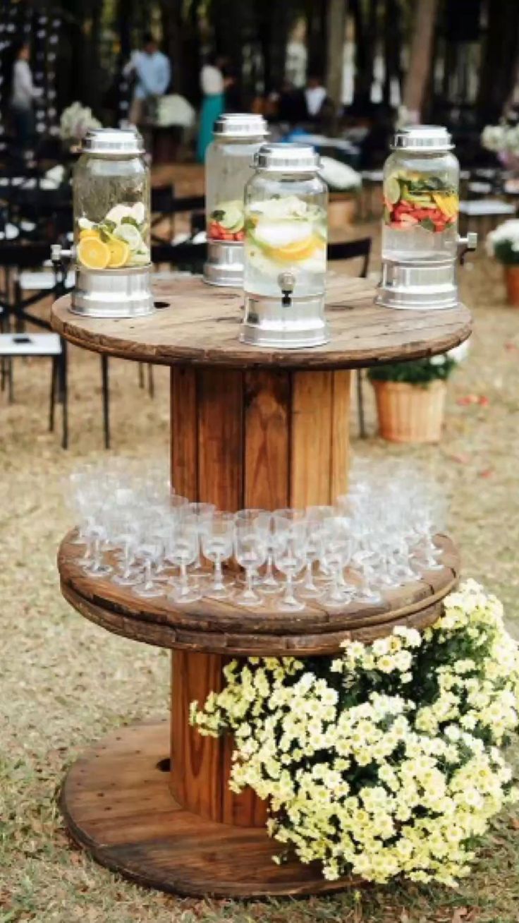 three tiered wooden table with glasses on it and flowers in vases next to them