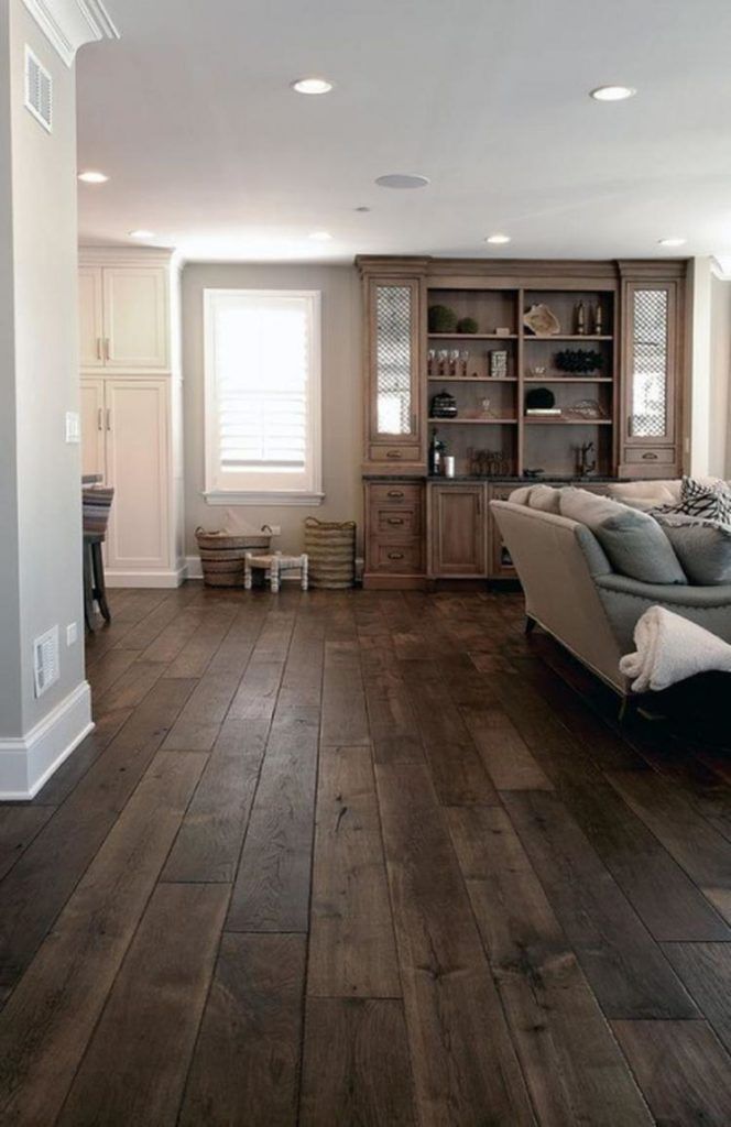 a living room with wood flooring and furniture in the center, along with a bookcase full of books