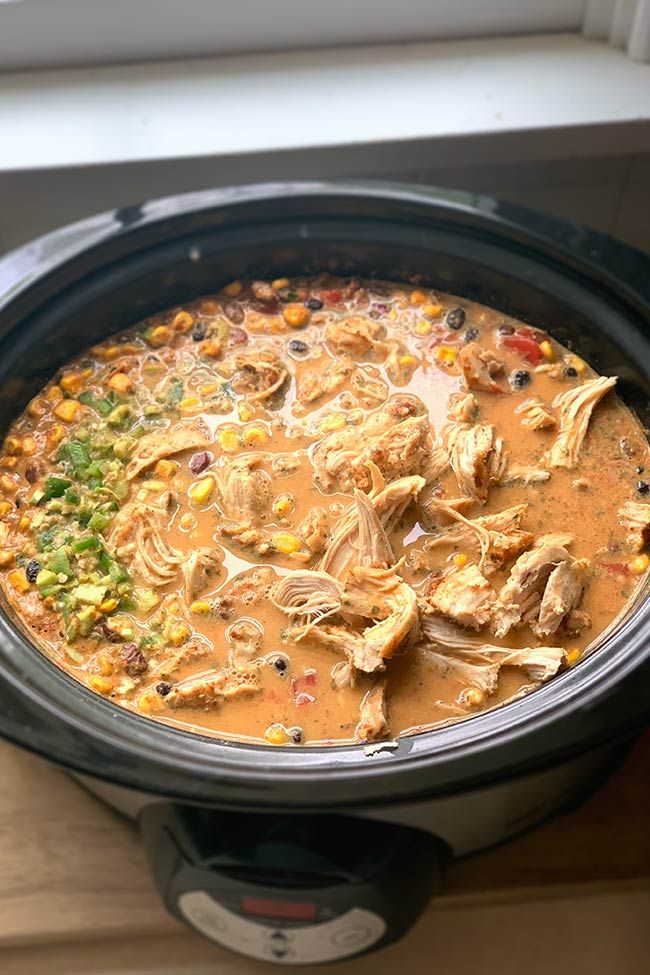 a crock pot filled with chicken and corn soup