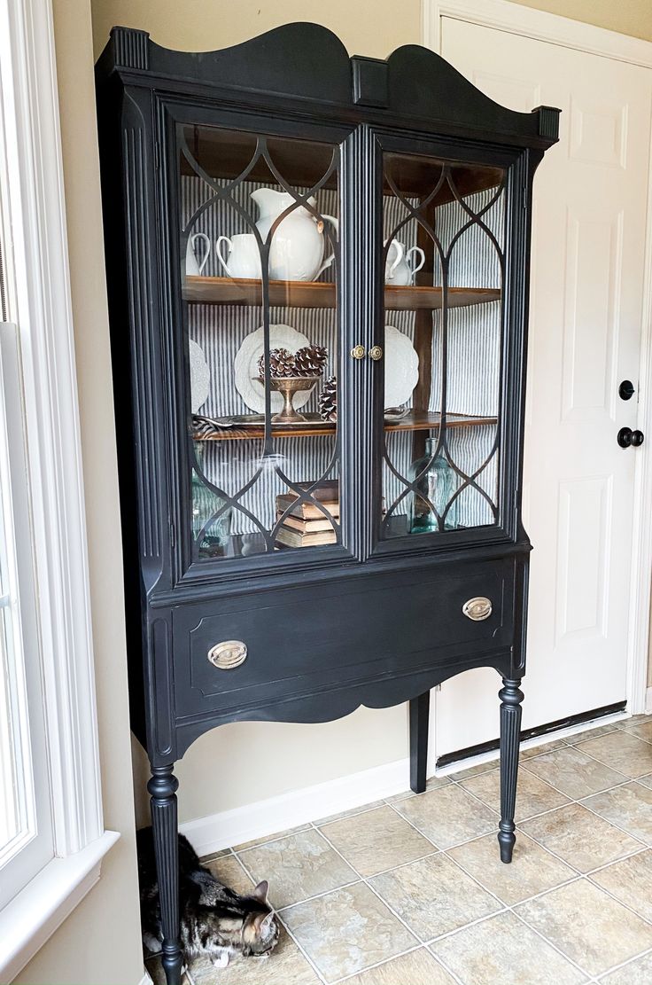 a black china cabinet with glass doors and shelves