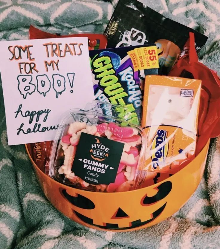 a halloween treat basket with candy, candies and greeting cards in it on a blanket