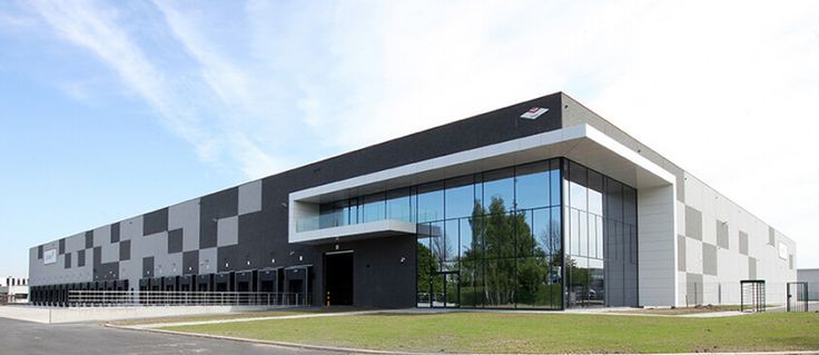 an empty parking lot in front of a large building with glass windows on the side