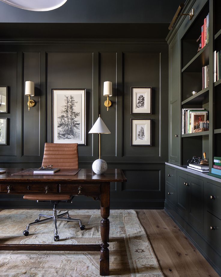 a home office with dark green walls and wood floors, along with an old fashioned desk