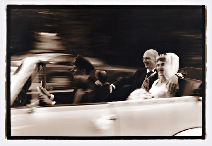 a man and woman riding in the back of a convertible car with other people behind them