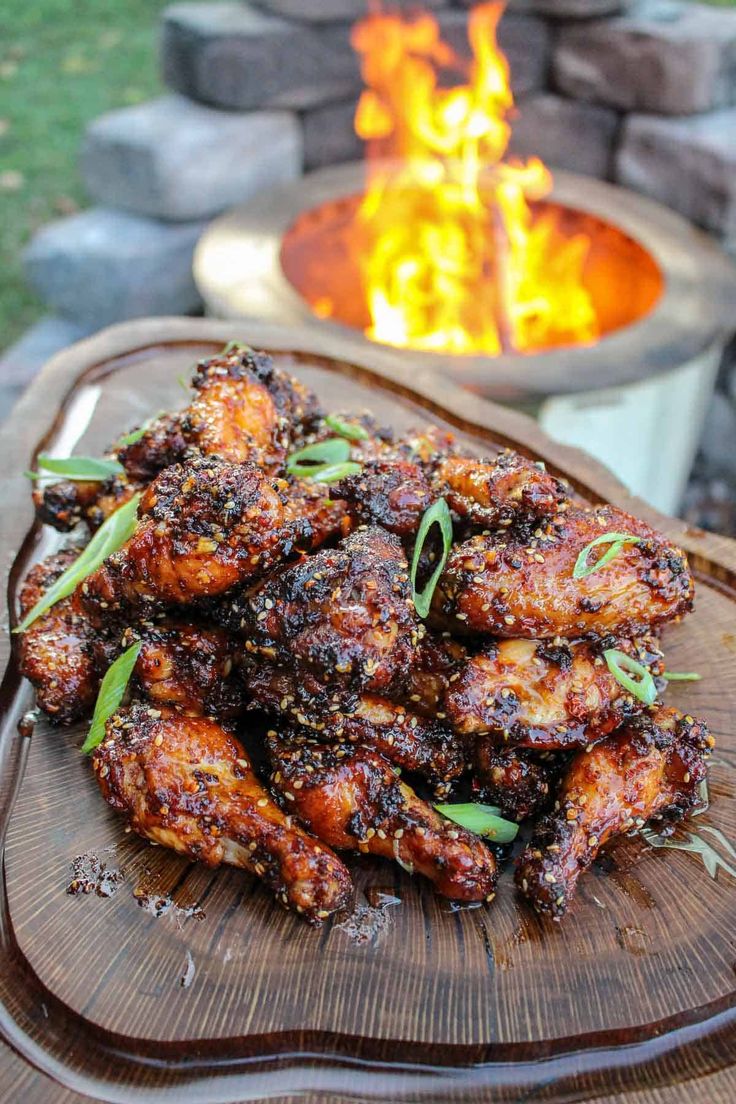 chicken wings on a platter next to an open fire pit