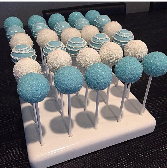 there are many blue and white cake pops on the table