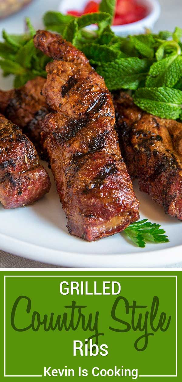 grilled country style ribs on a white plate with green garnish and tomatoes