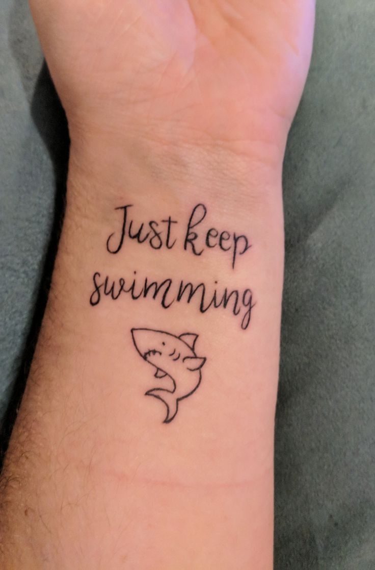 a wrist tattoo that says just keep swimming