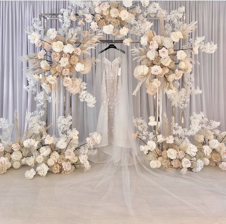 a wedding dress hanging in front of a floral arch