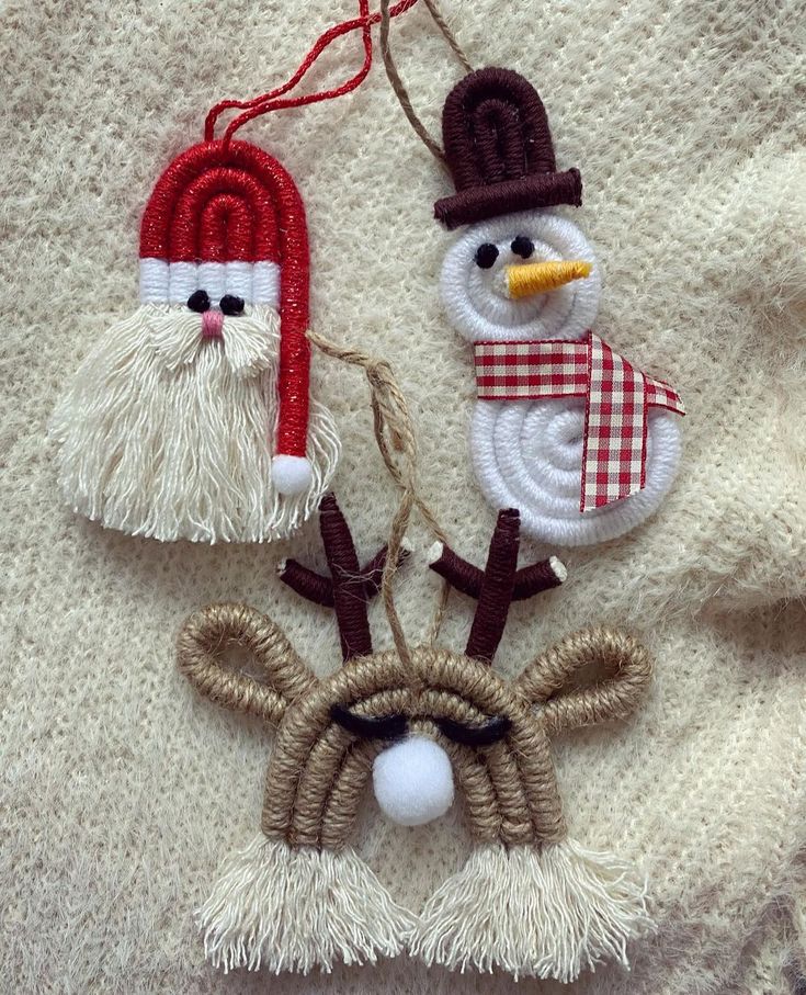 three christmas ornaments hanging on a white blanket with snowman, santa clause and reindeer