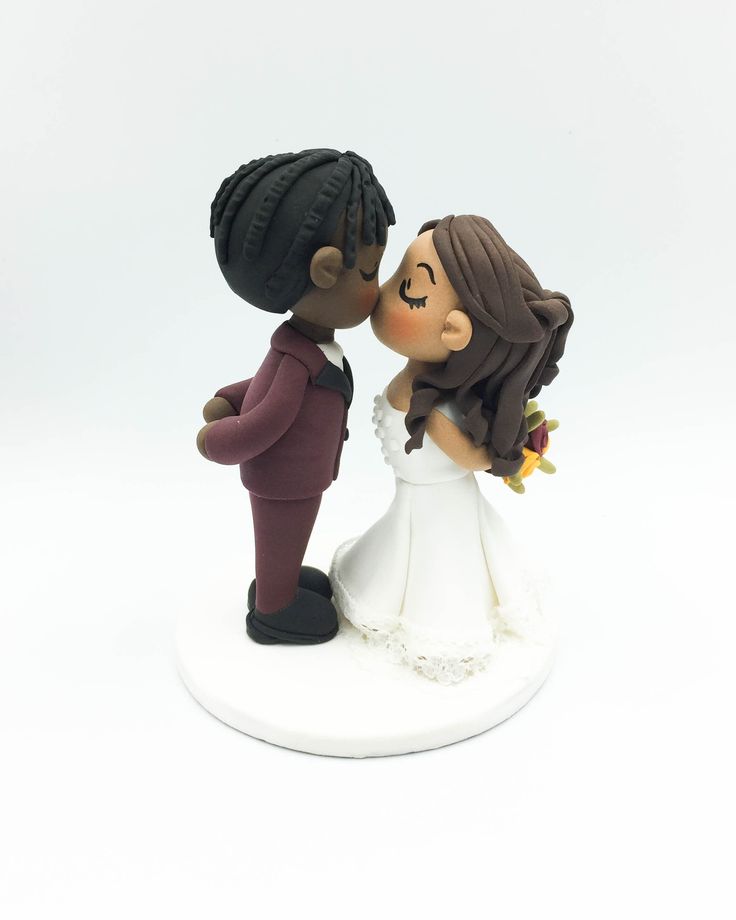 a wedding cake topper with a bride and groom kissing on the cheek, against a white background