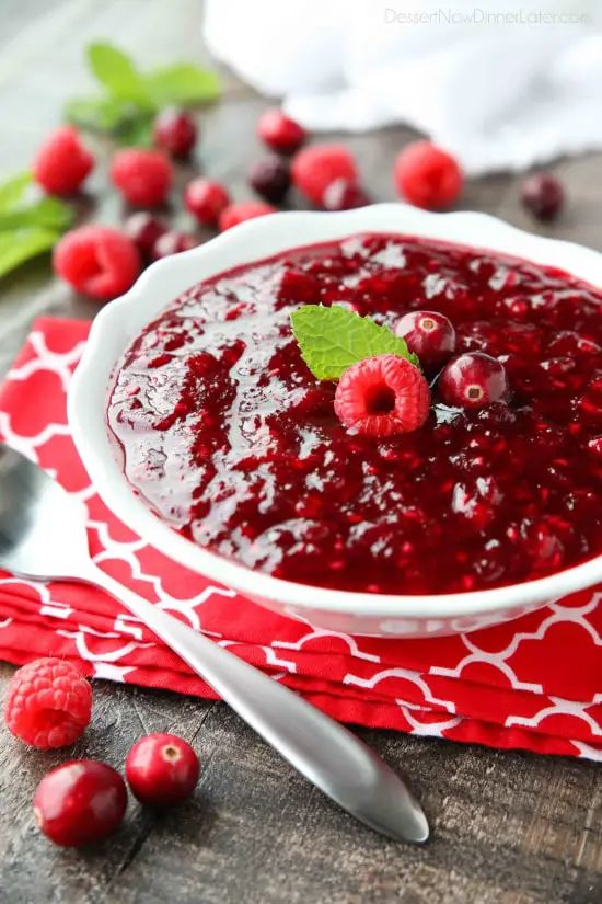 cranberry sauce in a white bowl with fresh raspberries on the side