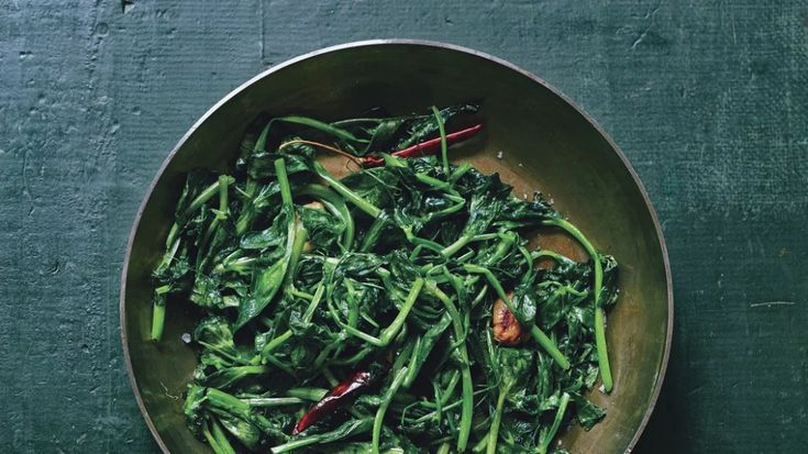 a bowl filled with green vegetables on top of a table