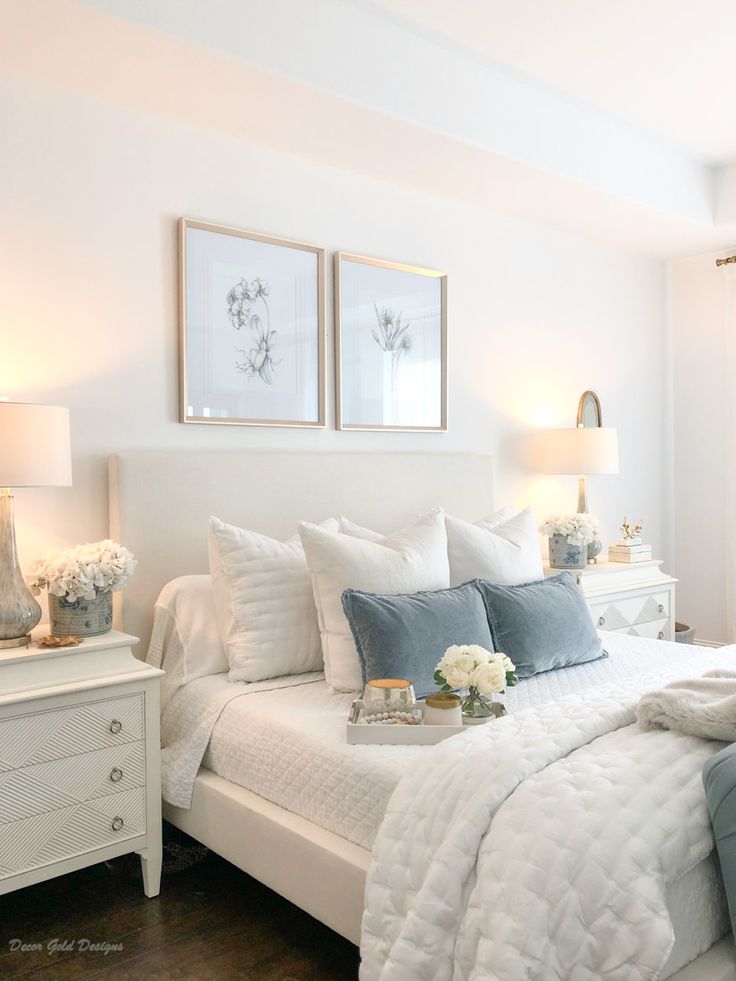 a bedroom with white bedding and blue pillows