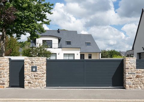 a house with stone walls and gate in front of it