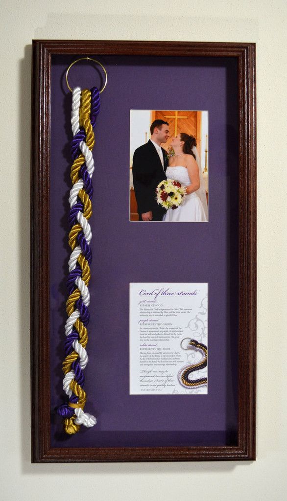 a purple frame holds a wedding photo and two braids as it hangs on the wall