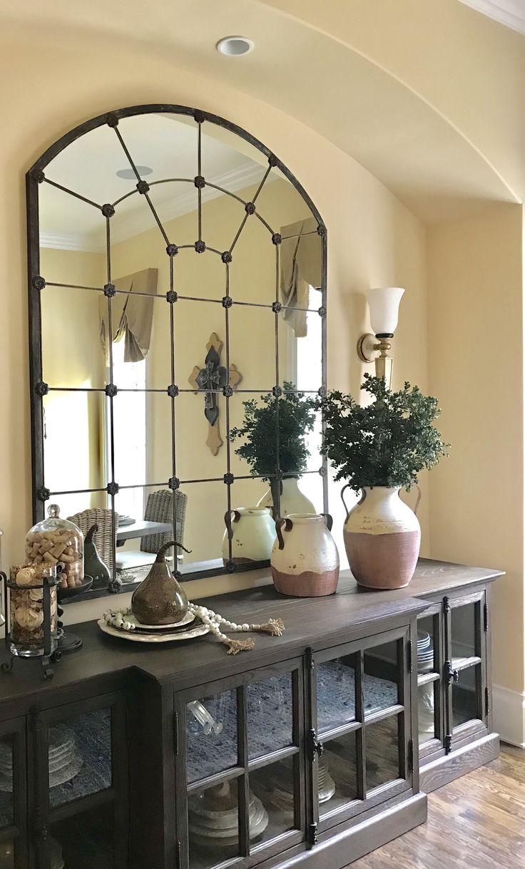 a large mirror sitting on top of a wooden table next to a vase filled with flowers