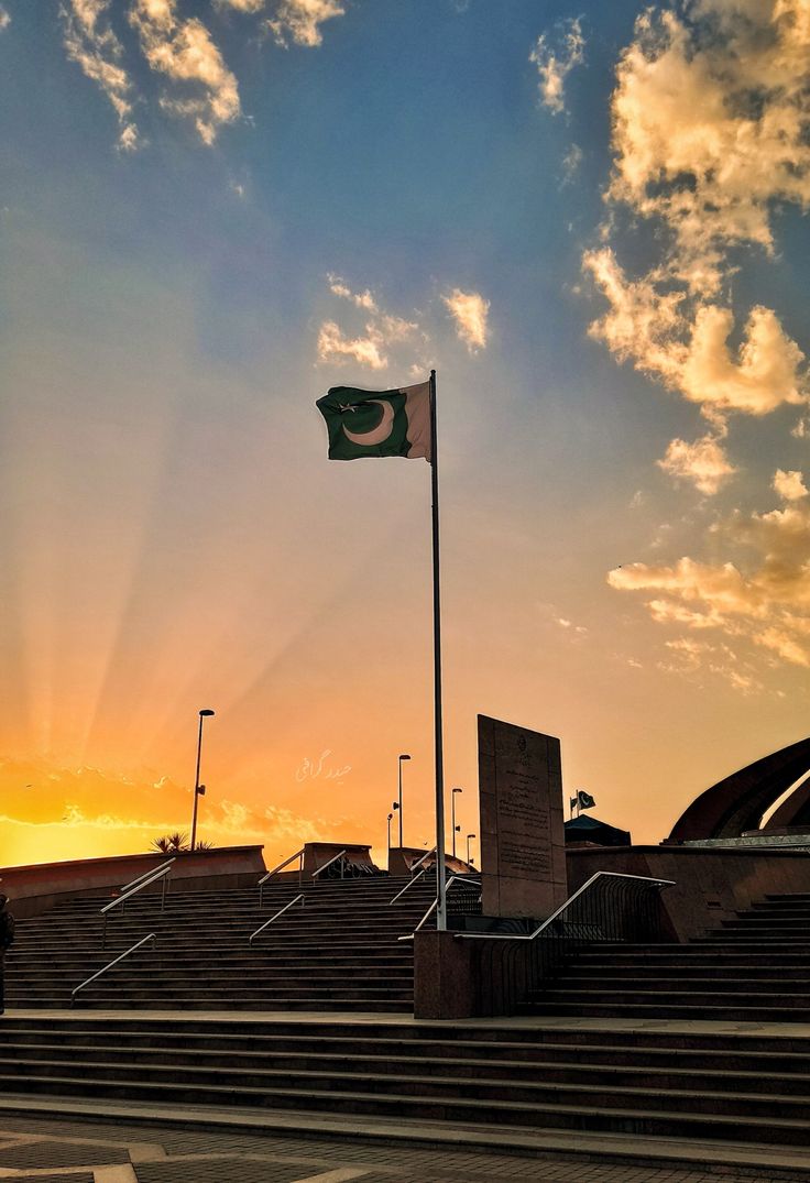 the sun is setting over some steps with a pakistan flag flying in the sky above