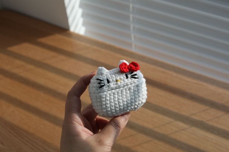 a hand holding a small knitted hello kitty doll