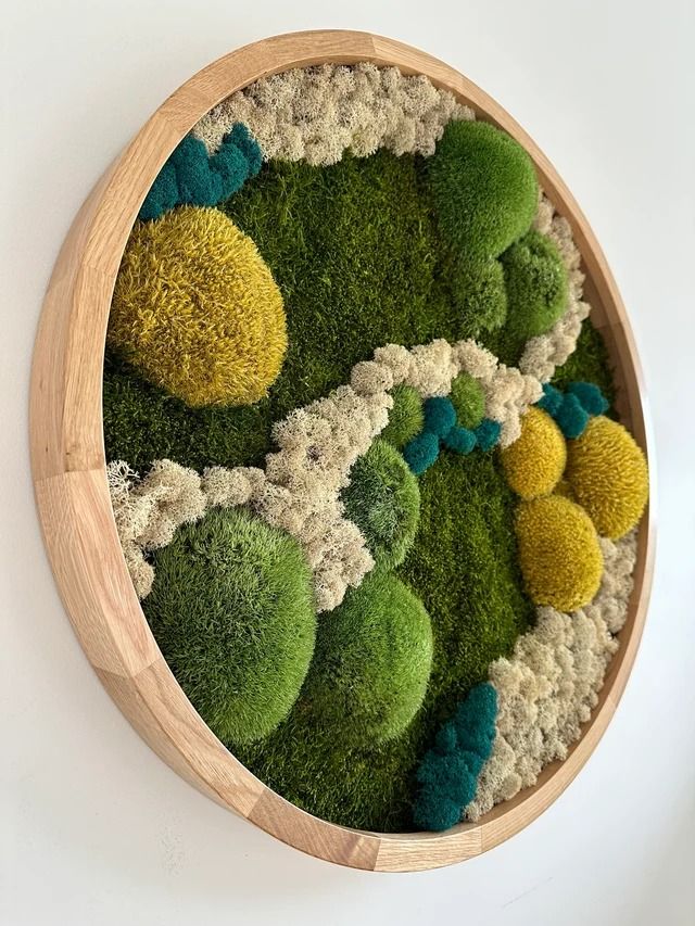 a wooden bowl filled with green and yellow flowers on top of a white wall next to a clock