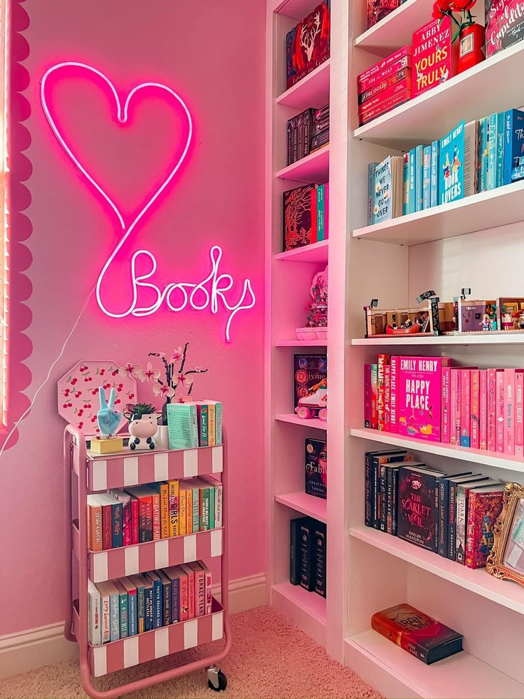 a pink room with bookshelves and a neon sign that says i love books