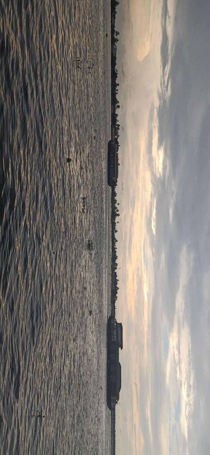 an airplane is flying over the water at sunset or sunrise, with clouds in the sky