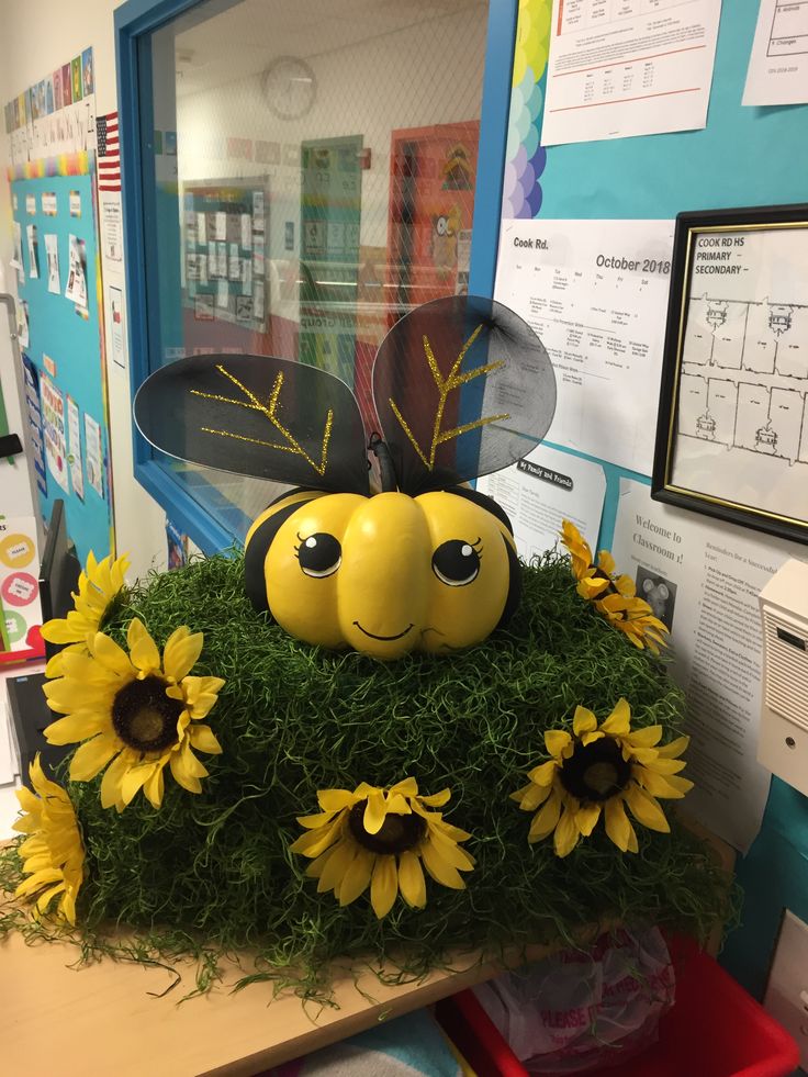 a yellow and black bee sitting on top of green grass covered in sunflowers