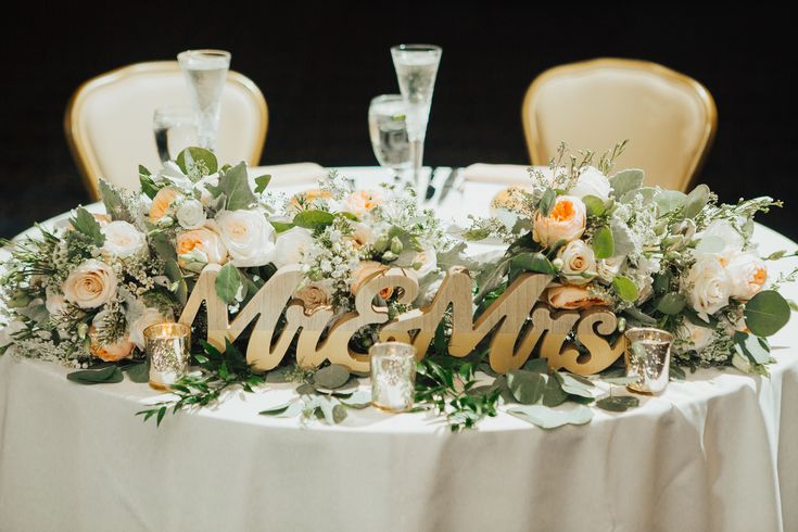 the table is set with flowers and mr and mrs signs