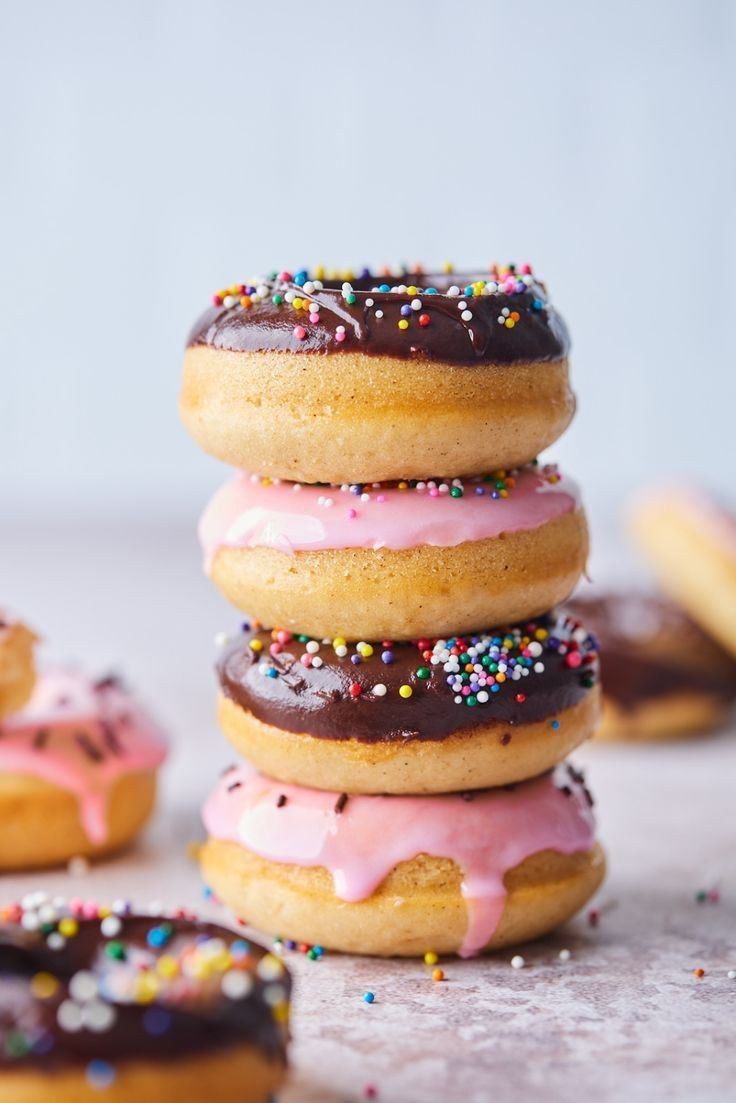 a stack of donuts with pink frosting and sprinkles