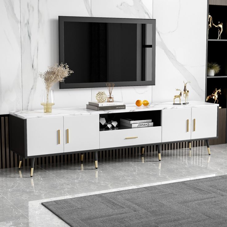 a white and black entertainment center in a living room with marble floors, gold accents