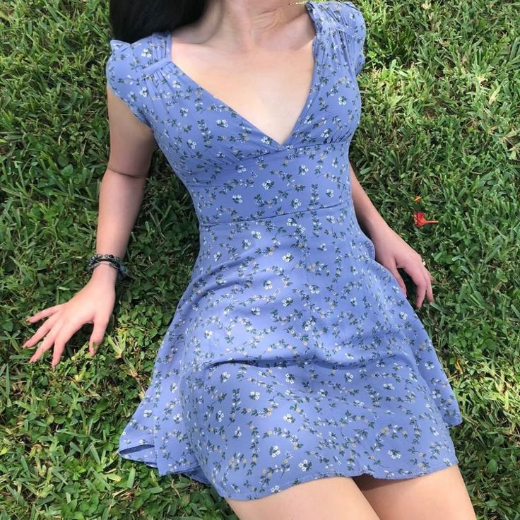 a woman laying on the grass wearing a blue dress