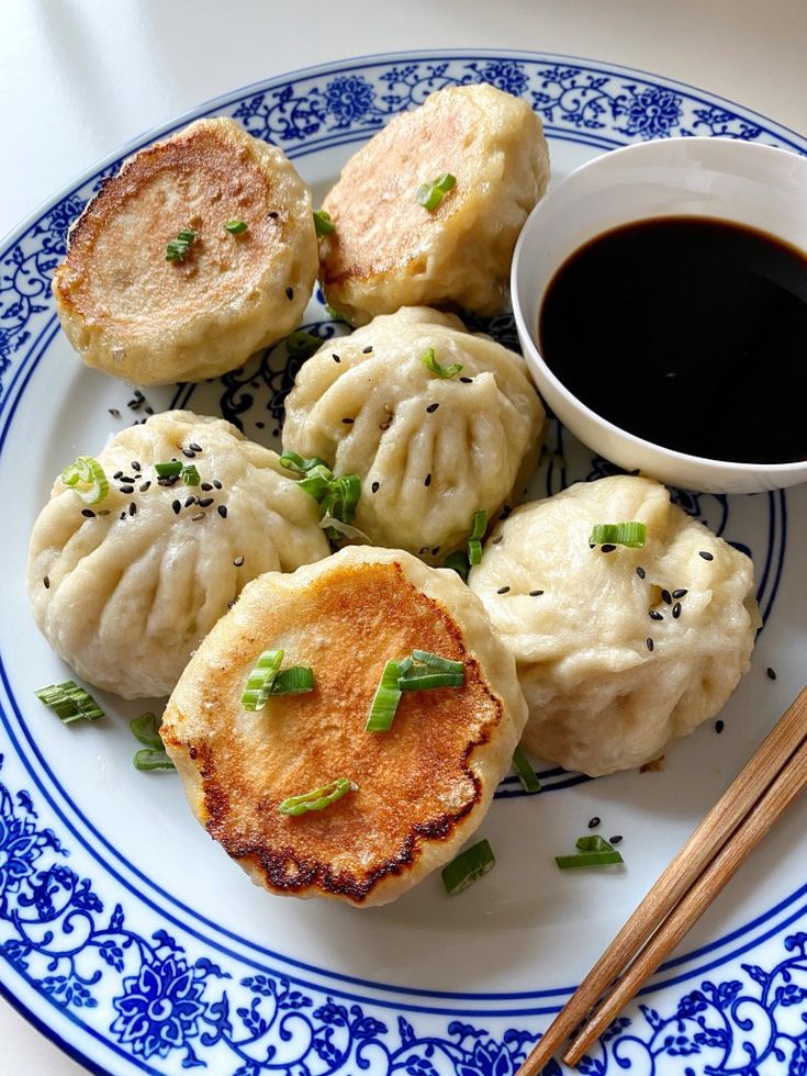 a blue and white plate topped with dumplings and dipping sauce