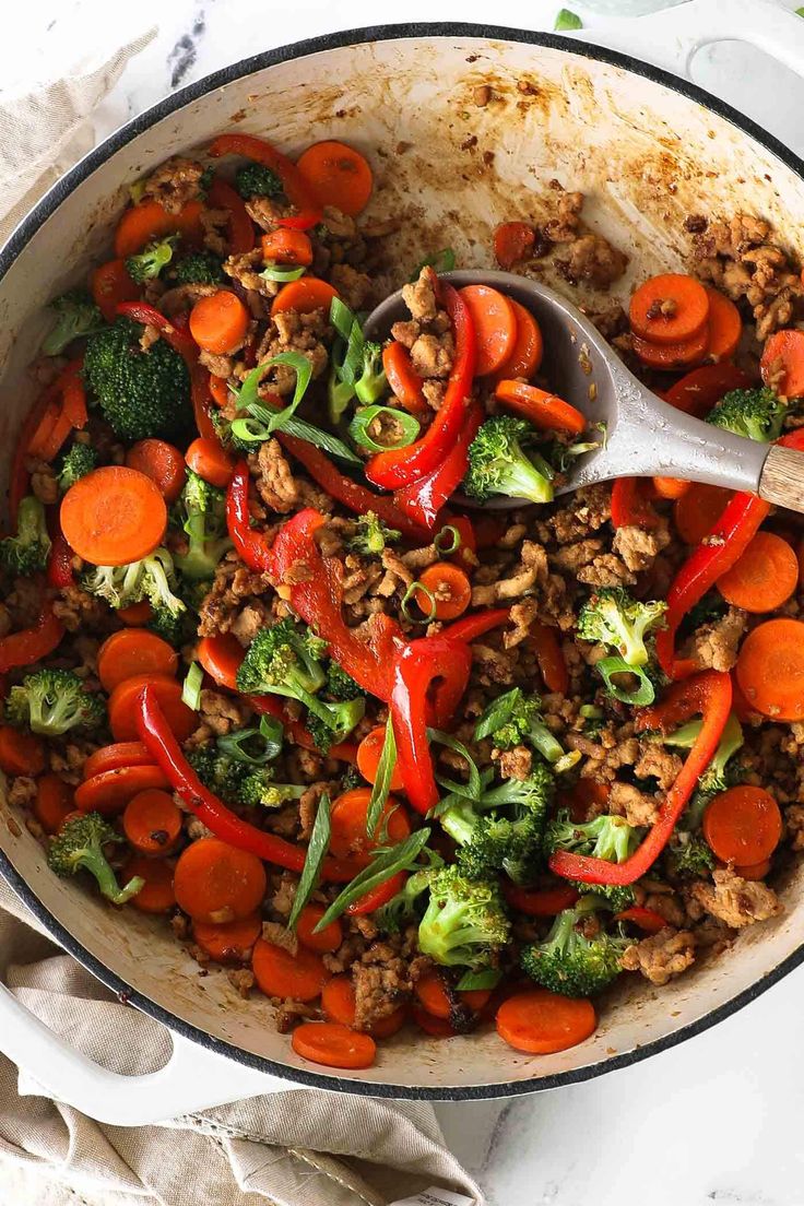 a skillet filled with stir fry vegetables and meat