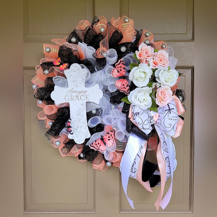 a wreath decorated with flowers and crosses is hanging on the front door to welcome someone