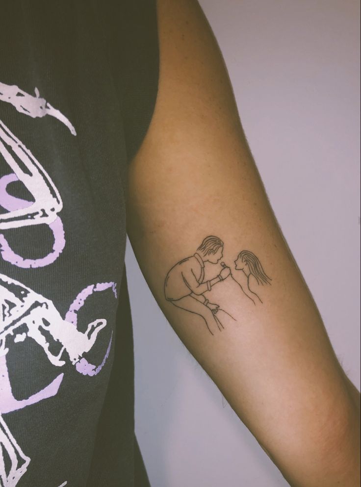 a woman's arm with a tattoo on it that has a drawing of a man kissing a woman