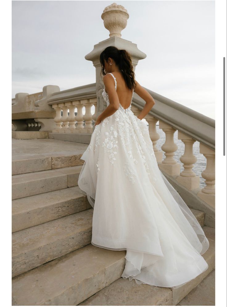 a woman in a wedding dress standing on some stairs