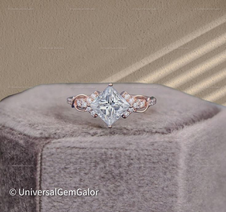 an engagement ring with a princess cut diamond in the center on top of a cushioned surface