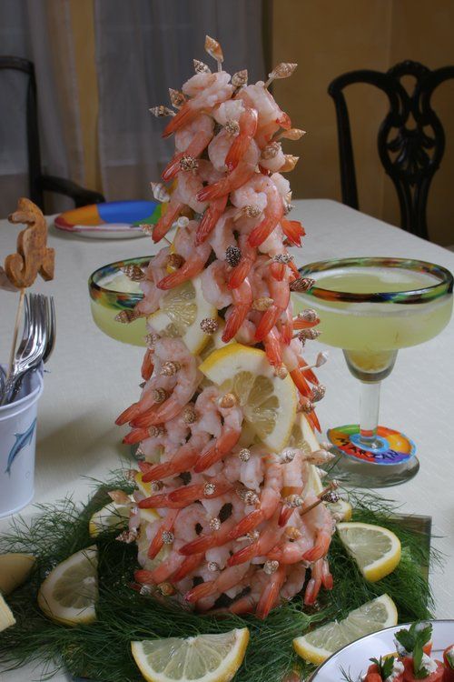 a christmas tree made out of shrimp and lemons on a table with other food