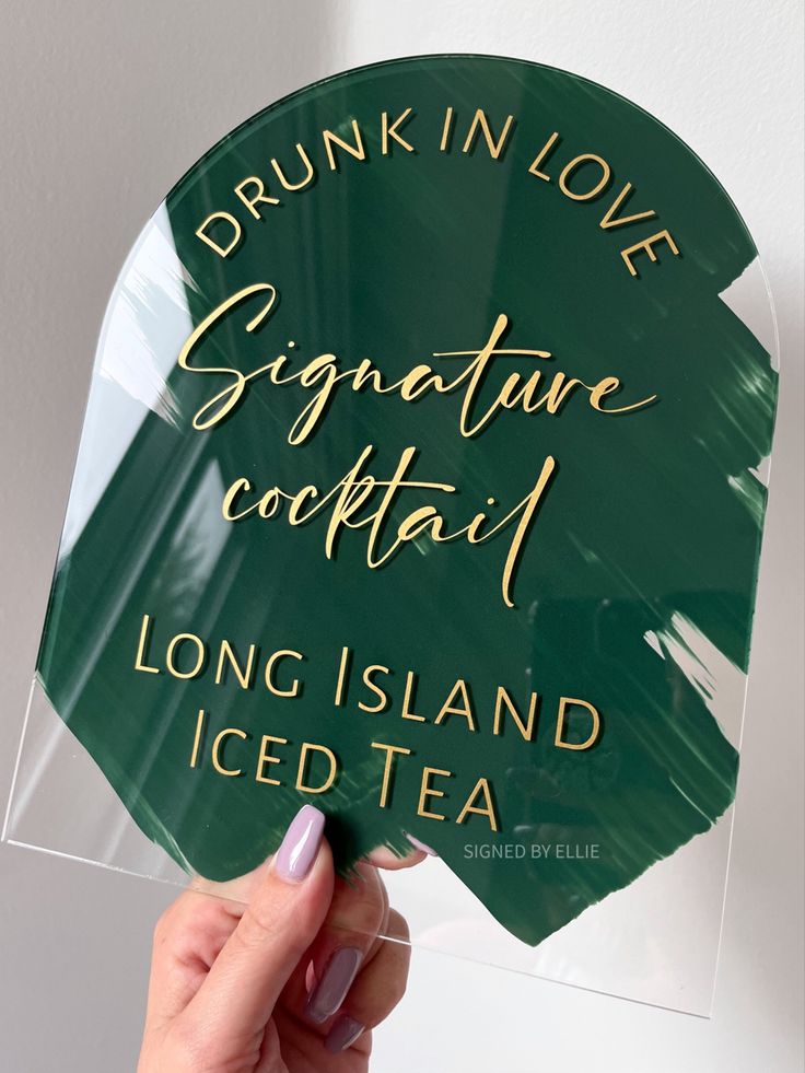 someone holding up a sign that says drink in love signature cocktail long island iced tea