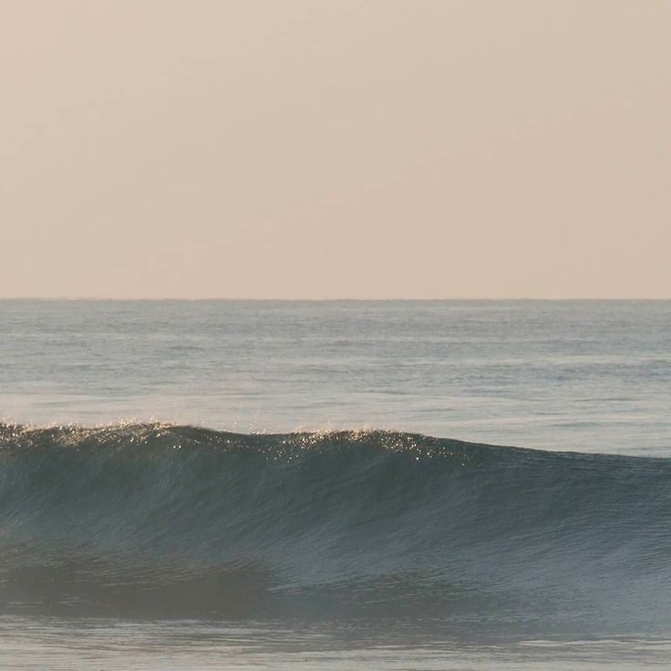 a man riding a wave on top of a surfboard in the middle of the ocean