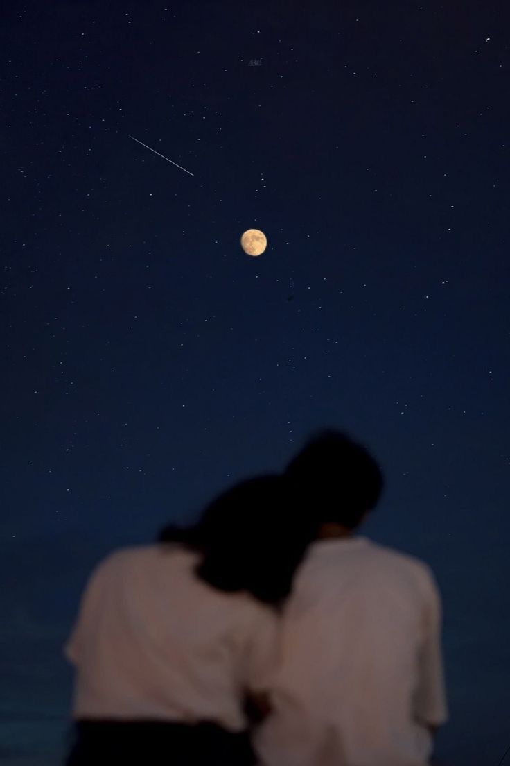 two people are looking up at the moon