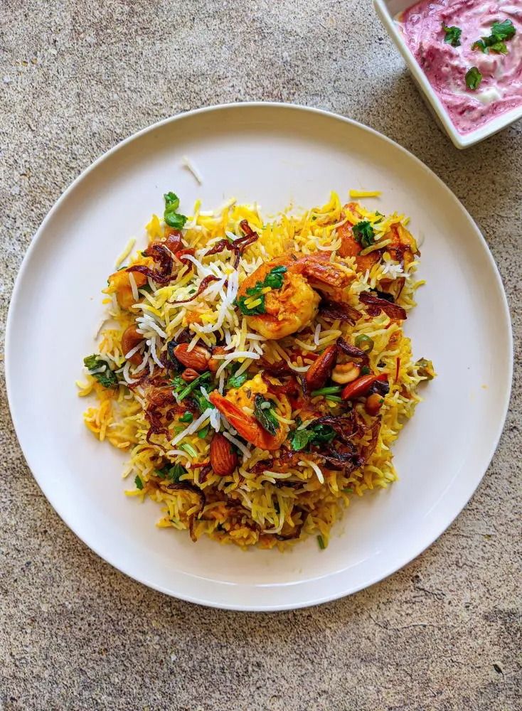 a white plate topped with rice covered in meat and veggies